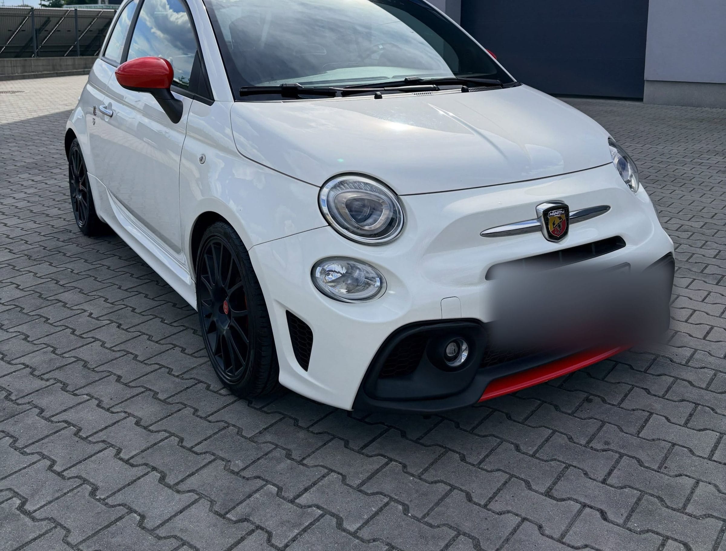 Biały Abarth 595 z czerwonymi lusterkami przed budynkiem GO+ w Modlnicy